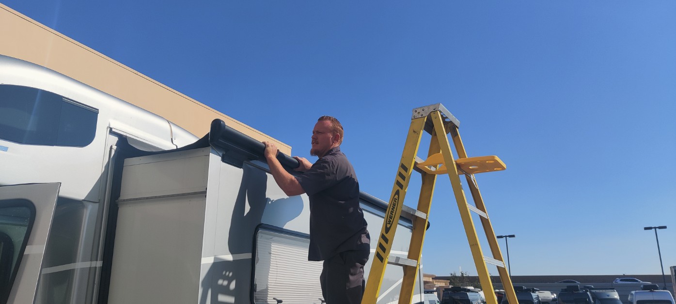 Giant RV technician installing a slide room topper